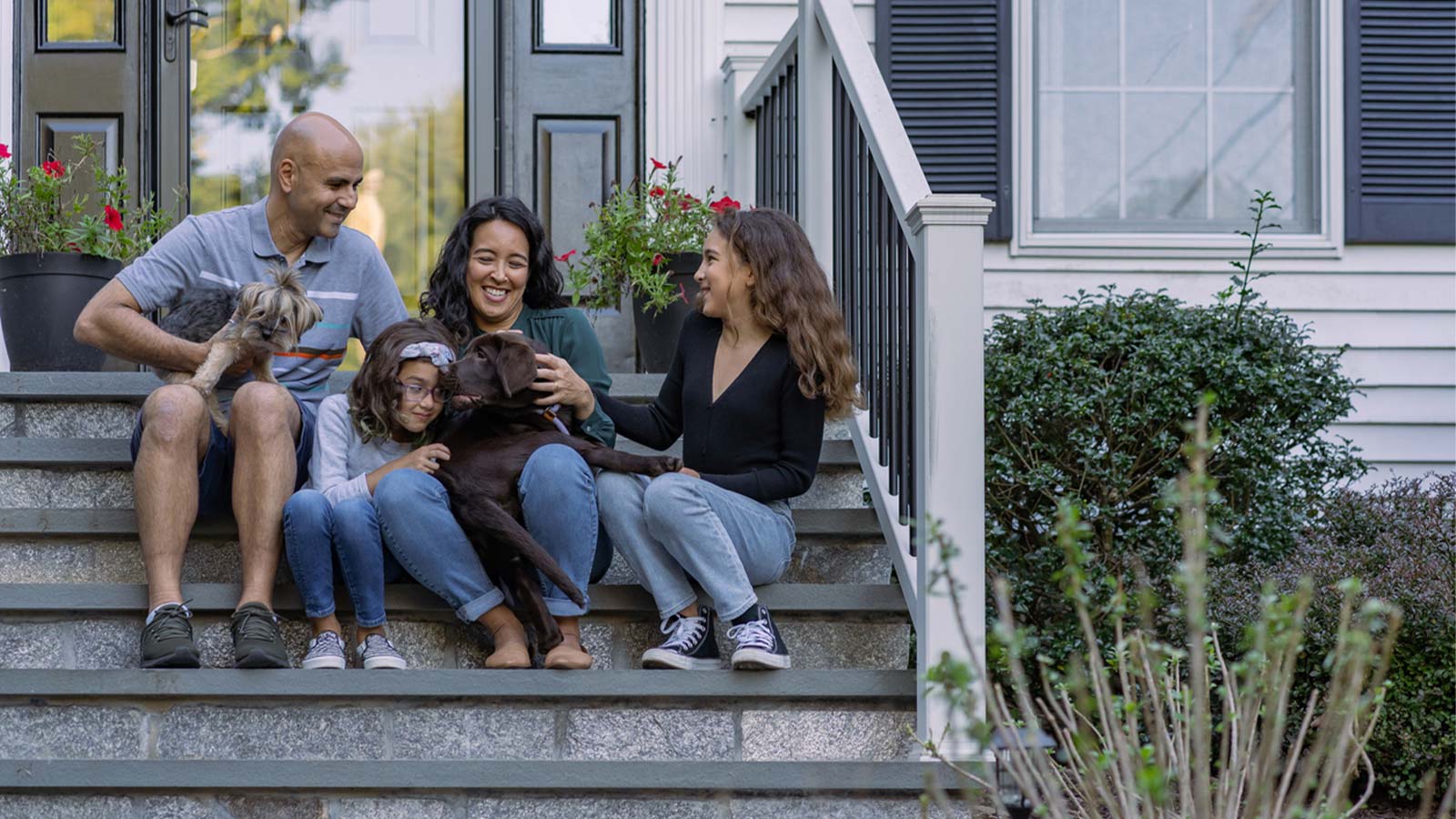 a happy family with their dog outside of their home