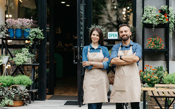 two flower shop owners smiling in front of their small business store